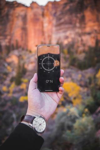 Person holding up a mobile device with a compass app open.