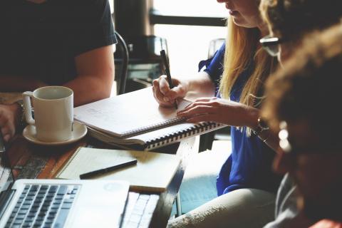 Meeting with people using laptops and paper notebooks