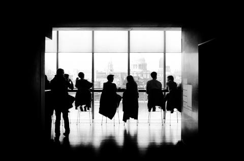 Black and white image of people in chairs in front of a large window