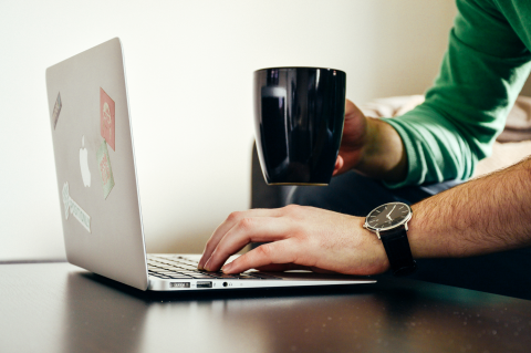 Working on a laptop with coffee cup in hand