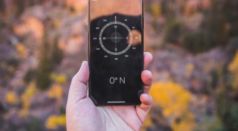 Person holding up a mobile device with a compass app open.