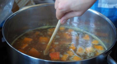Vegetable soup being stirred in a pot
